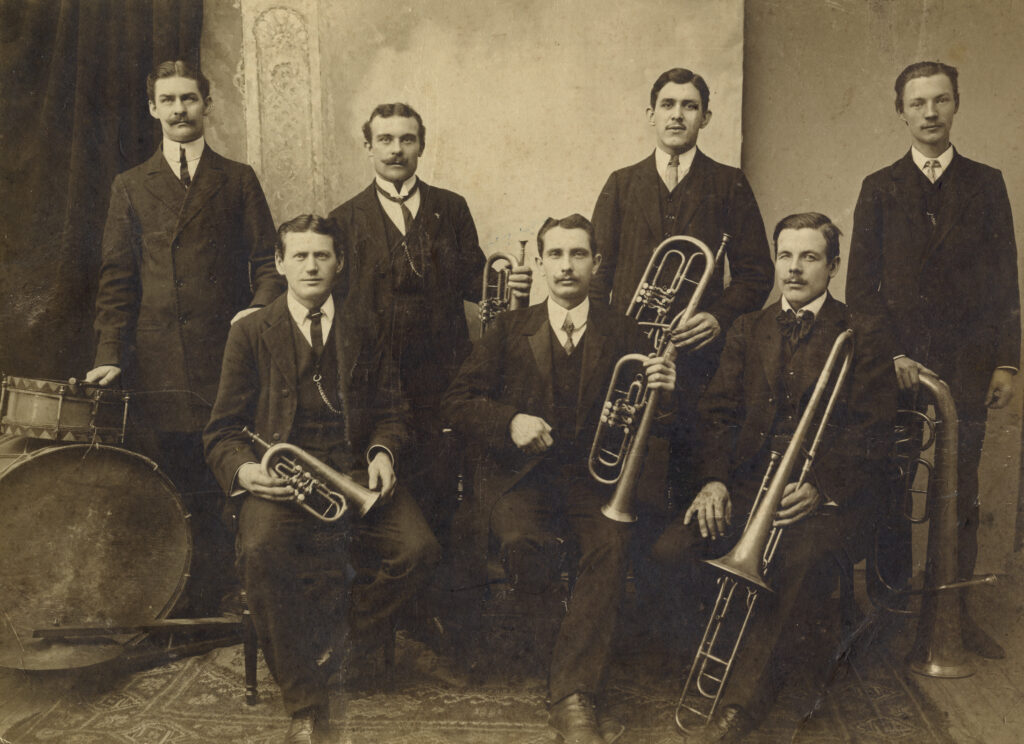 Gruppbild, de sju orkestermedlemmarna ömsöm sitter, ömsom står uppställda med sina instrument i händerna.
