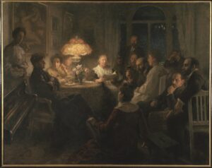 Män och kvinnor sitter runt ett bord som lyses upp av en ensam lampa. En kvinna läser ur en bok.
