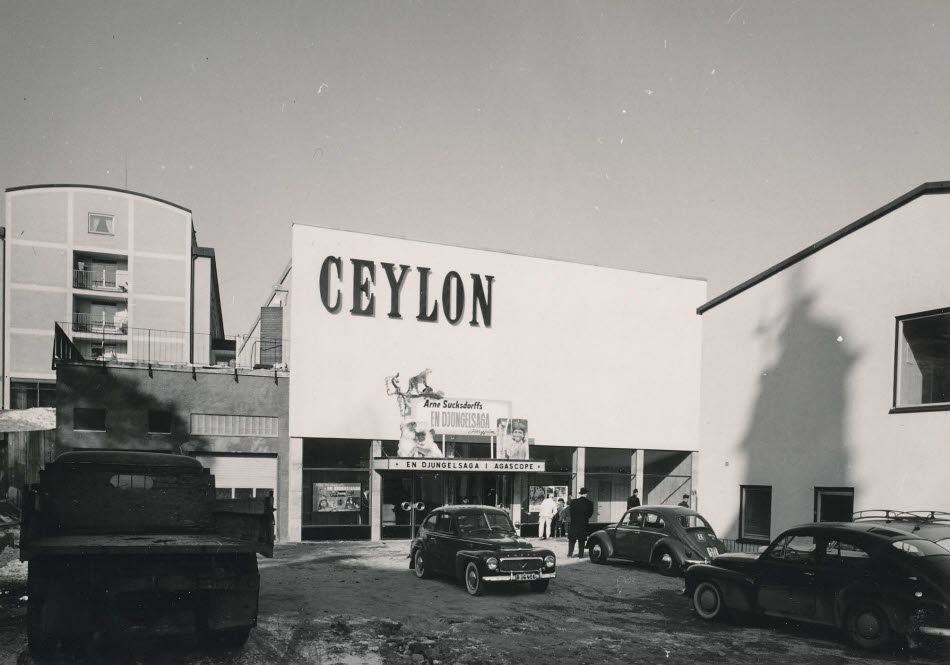 Biografens fasad har en undre del som är inskjuten och en övre del som är en stor, vit slät yta med texten CEYLON i högra hörnet.