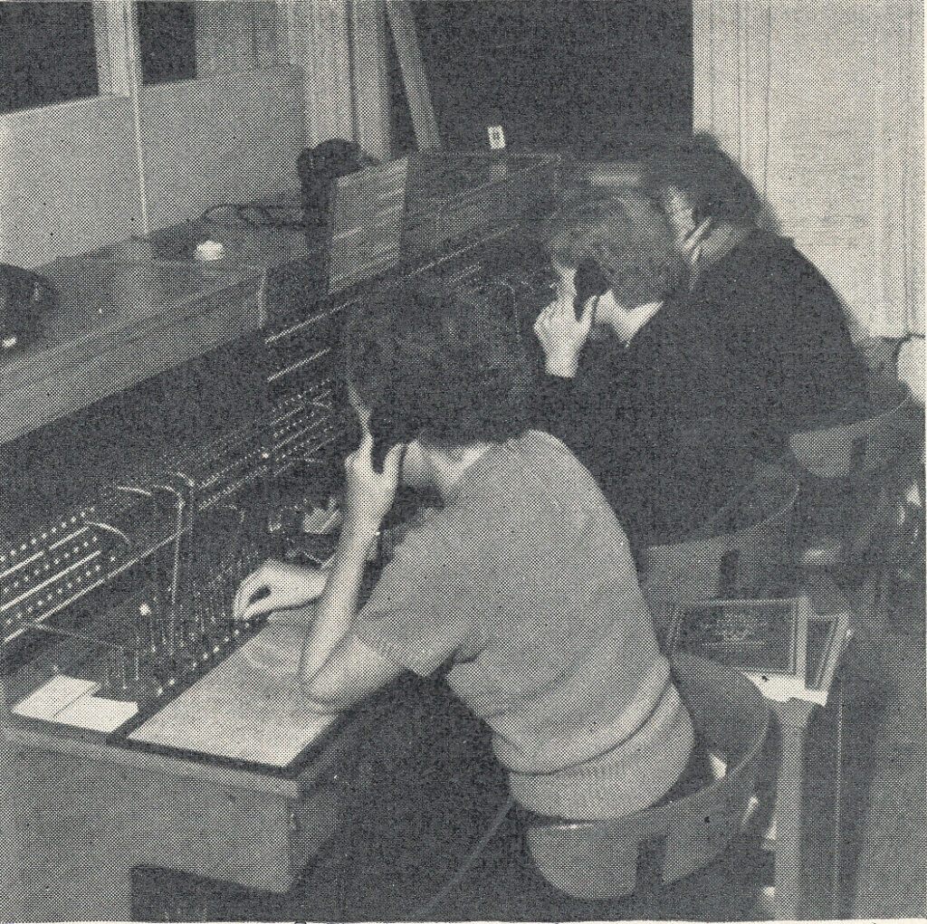 svartvitt foto av tre kvinnor som sitter böjda över en telefonväxel med ryggen mot kameran.