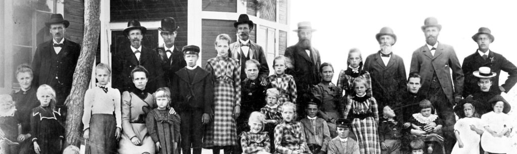 Ett svartvitt foto av barn och vuxna uppställda framför ett hus.
