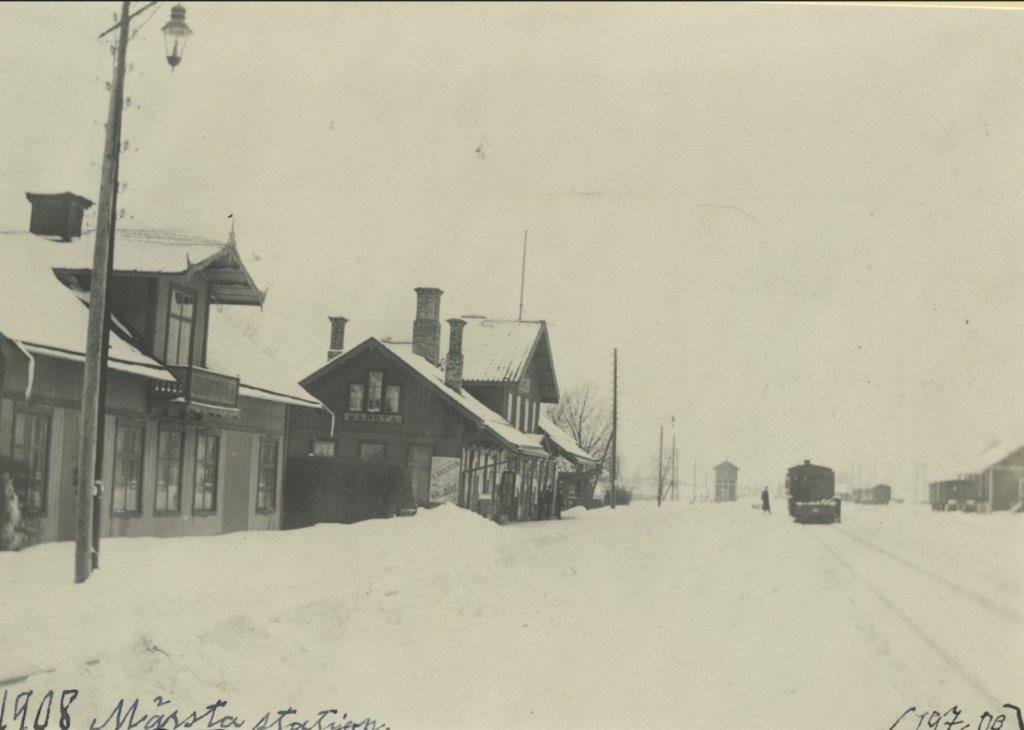 En svartvit bild av tågstationen med stora snövallar.