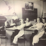 Svartvitt foto på barn vid skolbänkar