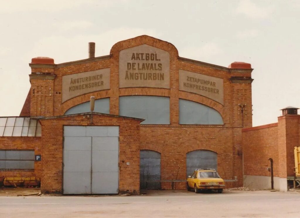 Ett gulnat färgfoto av fabriksbyggnad med igenspikade fönster.