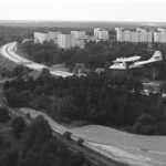 Planet flyger på låg höjd över Roslagsbanans spår, Norrtäljevägen och höghusen i Hägernäs.