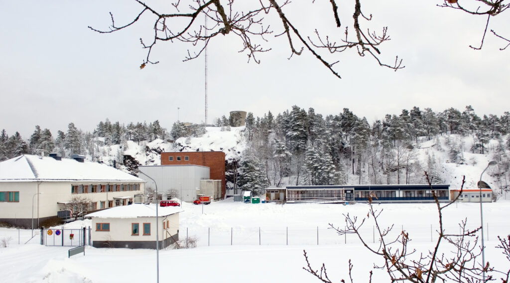 Flera olika byggnader vid bergets fot. På berget syns ett vattentorn och en mast.