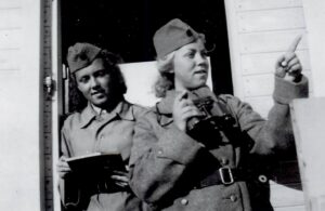 Två kvinnor i uniform, en med kikare.